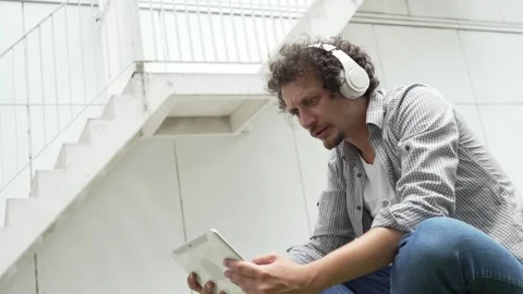 Man sit in front of building use digital tablet to watch movie podcast Stock Footage 248085927