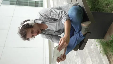 Man sit in front of building use digital tablet to watch movie podcast Stock Footage 248085968