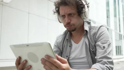 Man sit in front of building use digital tablet to watch movie podcast Stock Footage 248085970