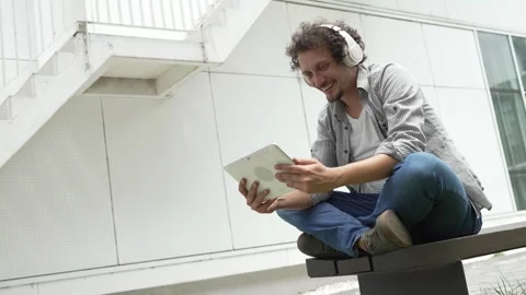 Man sit in front of building use digital tablet to watch movie podcast Stock-Footage 248085971