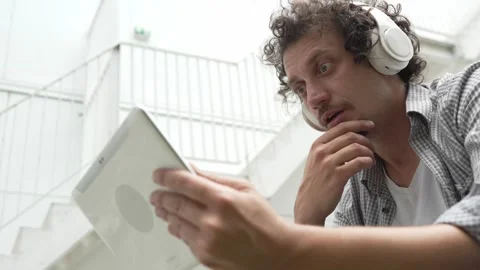 Man sit in front of building use digital tablet to watch movie podcast Stock Footage 248085989