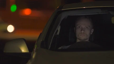 The man sit inside the car on the road. Evening night time. Left side traffic Stock Footage 74562309