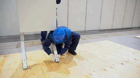 Man sit, screws key or ratchet racks legs of prefabricated parts to metal stand  Stock Footage 126356299