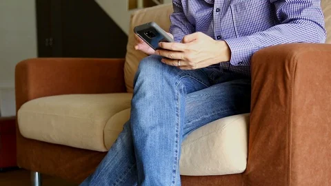 Man sit on sofa and using his smartphone Stock Footage 129175241