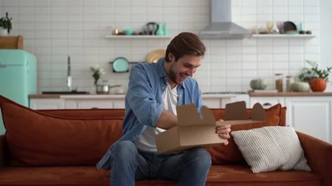 Man sit on sofa open delivered parcel sincerely glad on-line shop Stock Footage 142575392