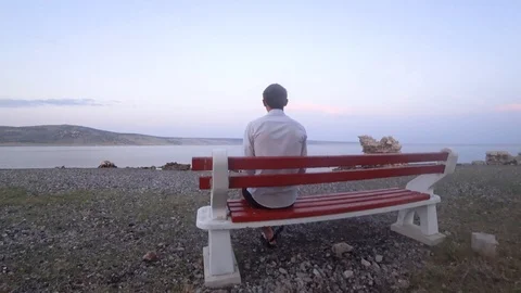Man sits alone on the bench in front of the sea watches the view Stock Footage 114222030