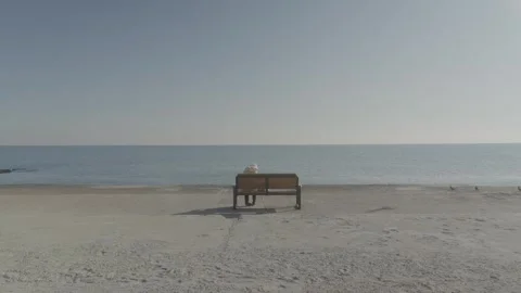 A man sits alone on a bench overlooking the sea Stock Footage 242491095