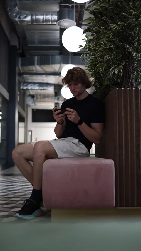 Man sits alone playing mobile games on smartphone focused on gameplay Stock Footage 345361123