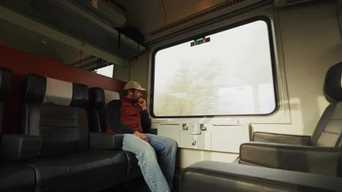 A Man Sits Alone on a Train, Looking Out the Window in Thought - Medium Shot Stock Footage 333795727