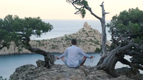A man sits and meditates between the pines high in the mountains Stock Footage 158310044