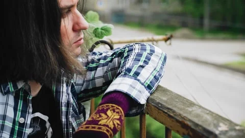 A man sits on the balcony leaning on the railing and looks around Stock Footage 131058014
