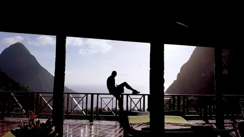 A man sits on a balcony of a luxury hotel room at St. Lucia Caribbean. 库存影片 113687579