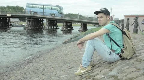 A man sits on the bank of the river. Stock Footage 52068596