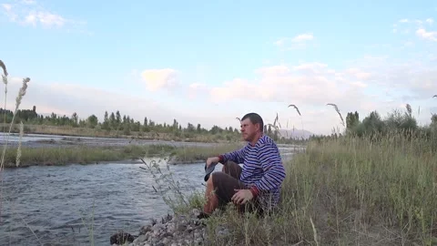 A man sits on the banks of the river. Stock Footage 148164994