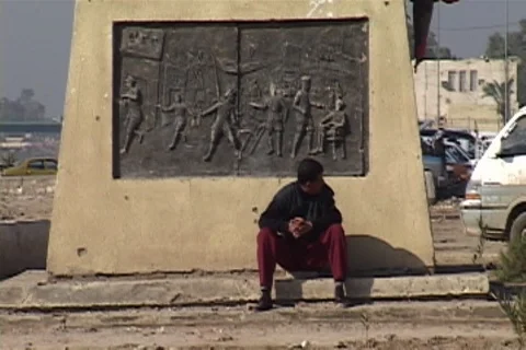 Man sits at base of statue in downtown Nasiriyah Stock Footage 86753702