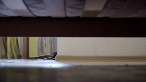 Man sits on a bed and goes to sleep. View from under the bed. Stock Footage 109116352