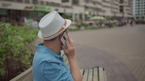 A man sits on a bench and talks on a cell phone Stock Footage 152661787