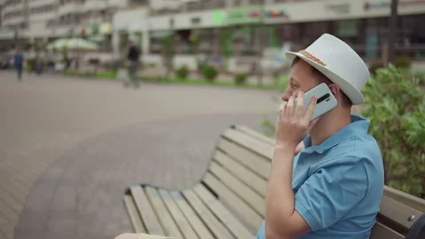 A man sits on a bench and talks on cell phone Stock Footage 152795097