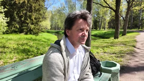 A man sits on a bench in a spring park on a sunny day 스톡 동영상 311120805
