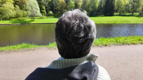 A man sits on a bench in a spring park on a sunny day 스톡 동영상 311120860