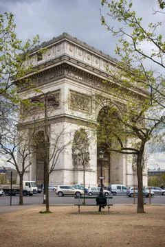 A man sits on a bench in the square in front of the Arc de Triomphe in Paris Stock Photos