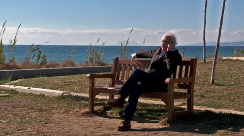 Man sits on bench taking phone call.    Stock Footage 39420673
