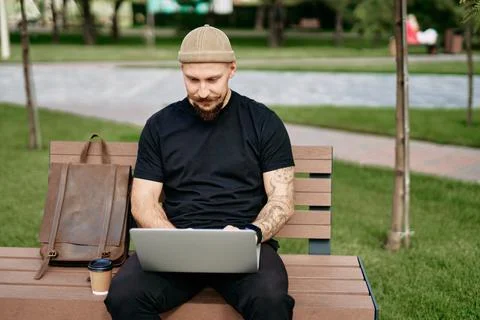 Man sits on the bench working, uses laptop with graphics, charts, diagrams on Stock Photos