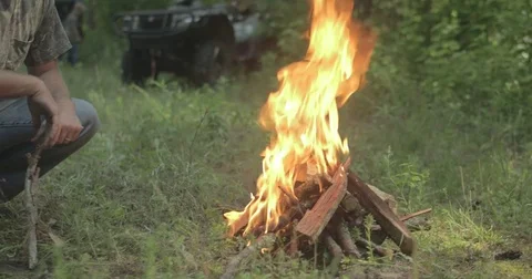 Man sits beside campfire in the forest Stock Footage 76703256