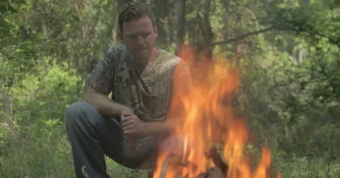 Man sits beside campfire in the forest Stock Footage 76703305