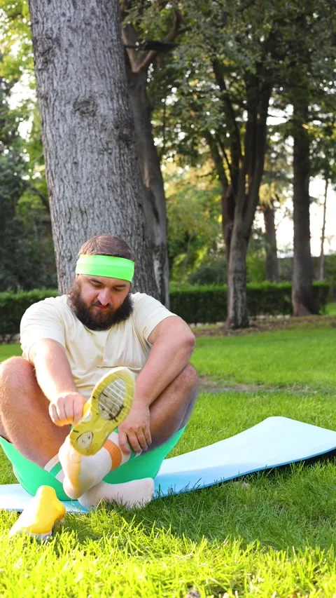 Man sits on blue mat, takes off his yellow sport sneakers Vídeo Stock 337831930