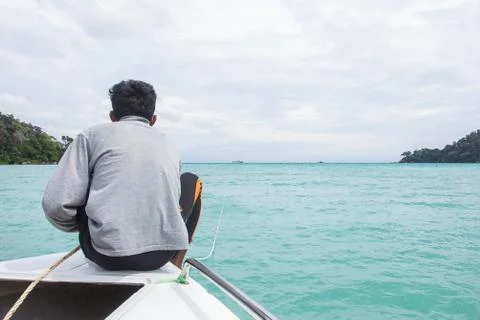 Man sits on a boat front while crossing Andaman. Stock Photos