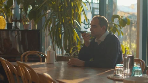 Man sits in cafe and records a voice message Stock Footage 120723964