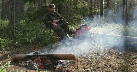 A man sits at a campfire Video stock 64803172