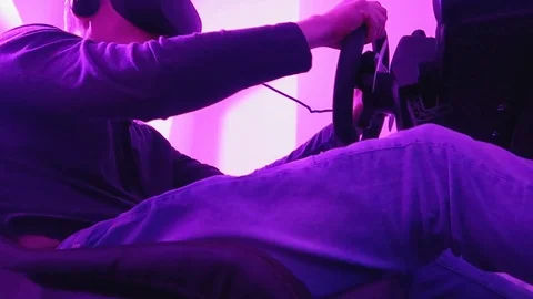 Man sits on a car simulator wearing VR glasses, Virtual Reality Stock-Footage 99225611