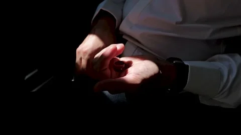 The man sits on a chair around the window and holds two rings in his hand. Stock Footage 288405662