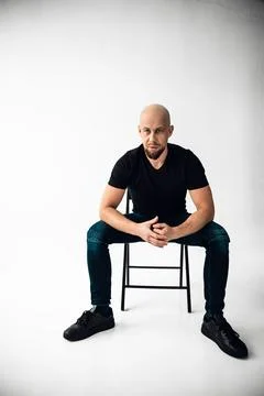 Man sits on chair in studio with plain background during a photo session in Stock Photos