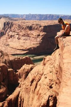 Man sits cliff edge Stock Photos