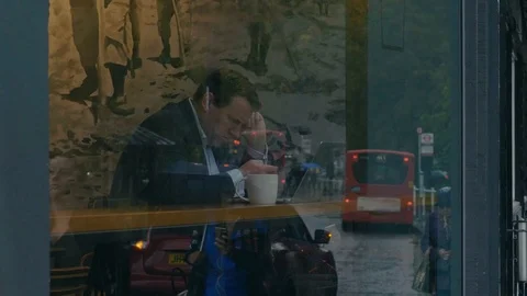 Man sits in coffee shop using a mobile phone though a window Stock Footage 88955672