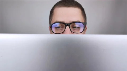 The man sits at the computer and stares intently at the monitor. The eyes move t Stock Footage 138363306