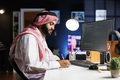 Man sits at a computer displaying codes Stock Photos