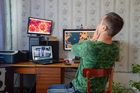 A man sits at computer monitors and is horrified by the news about the spread Stock Photos