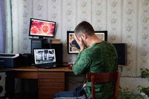 A man sits at computer monitors and is horrified by the news about the spread Stock Photos