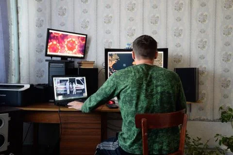 A man sits at computer monitors and is horrified by the news about the spread Stock Photos