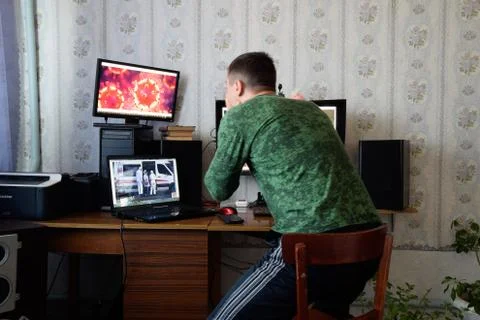 A man sits at computer monitors and is horrified by the news about the spread Stock Photos