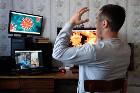 A man sits at computer monitors and is horrified by the news about the spread Foto stock
