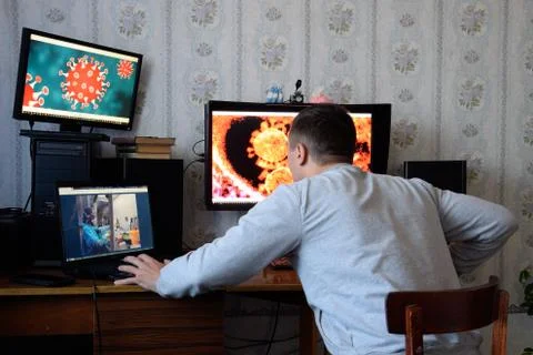 A man sits at computer monitors and is horrified by the news about the spread Stock Photos