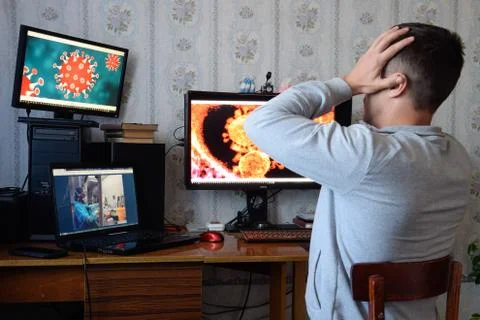A man sits at computer monitors and is horrified by the news about the spread Stock Photos