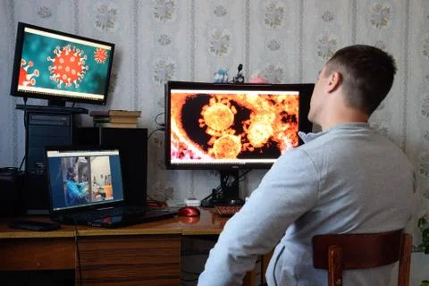 A man sits at computer monitors and is horrified by the news about the spread Stock Photos