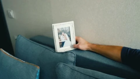 A man sits on the couch and looks pensively at his wedding photo and digests it Stock Footage 169302736