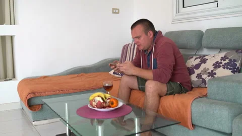 A man sits on a couch and uses a smartphone Video stock 100713097